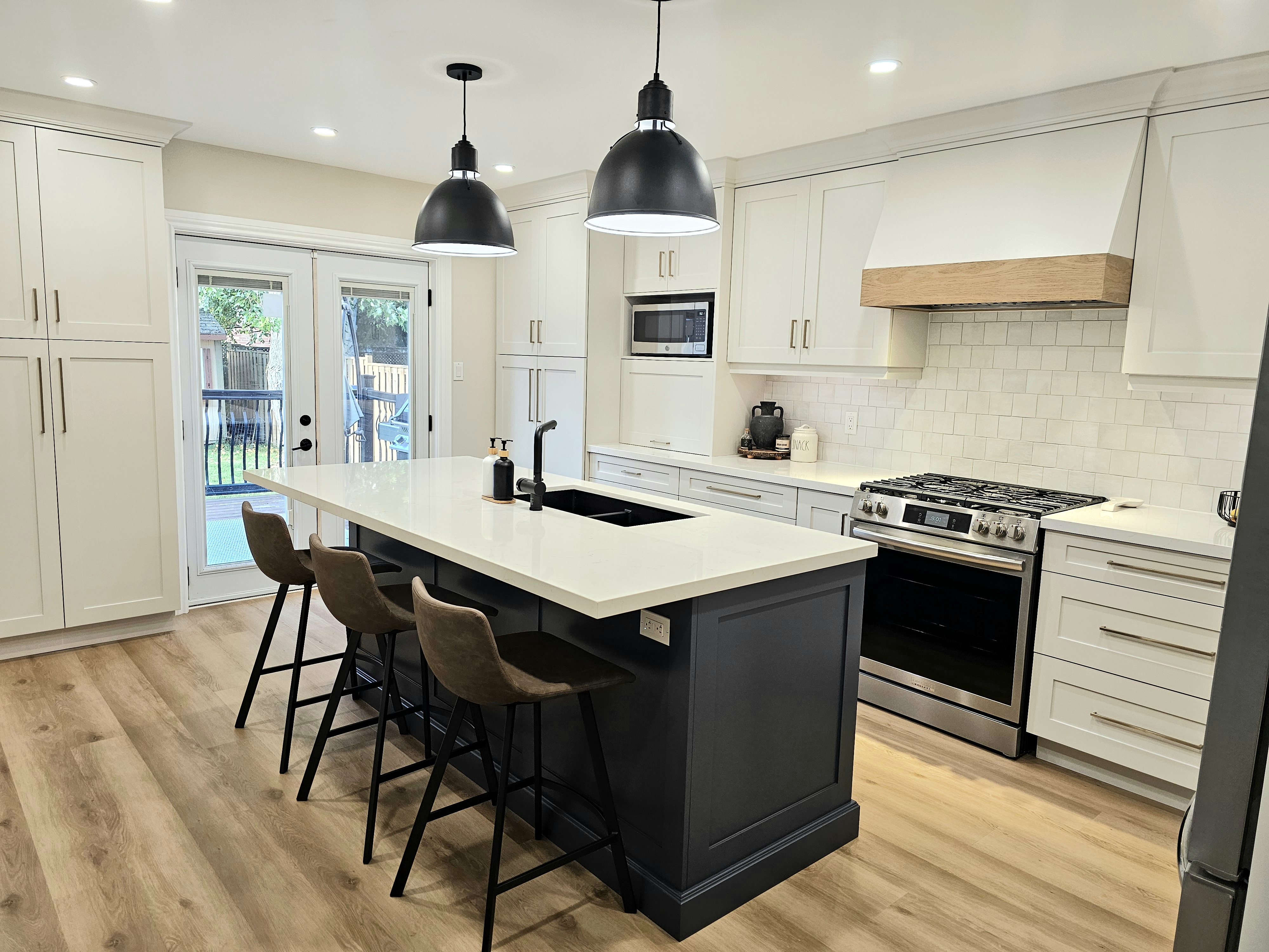 White kitchen with navy island and black dome pendants