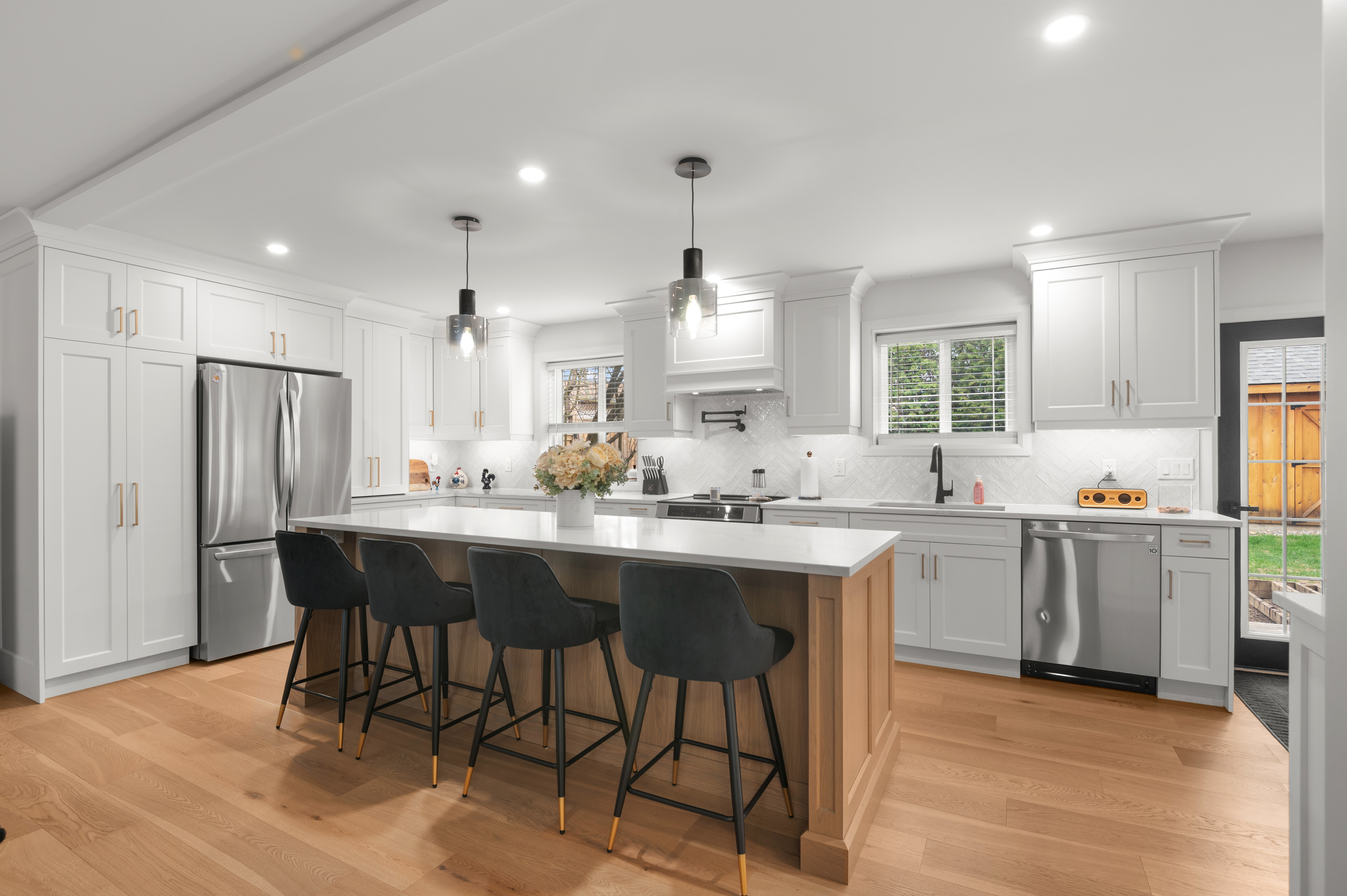White kitchen with natural wood island and black pendants